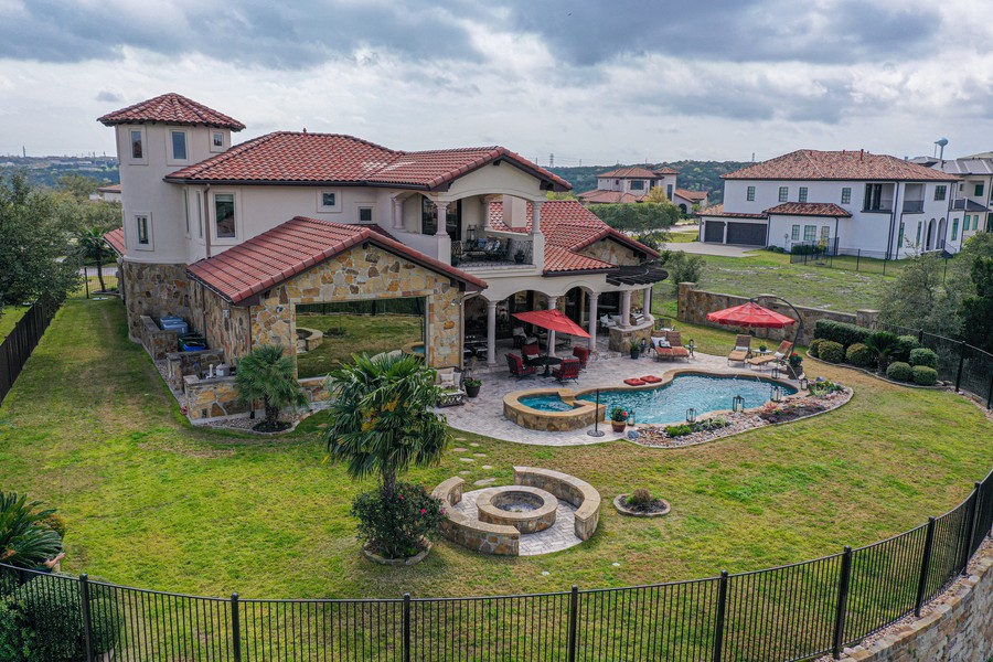 aerial view of a two-story home’s backyard with a firepit and pool area