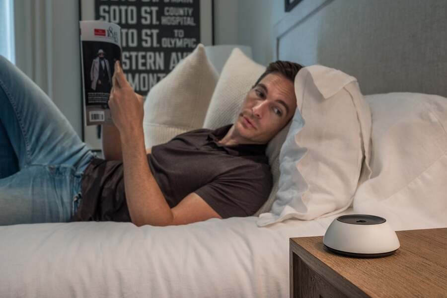 A man rests in his bed while controlling his home devices through a Josh.ai system.